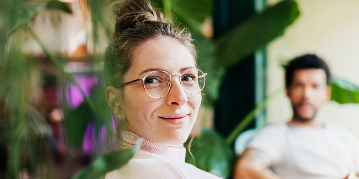 woman in office smiling, next to plants